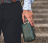 Man Holding Leather Wrist Bag from Rydal in 'Green'.