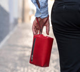 Man Carrying Leather Wrist Bag from Rydal in 'Red'.