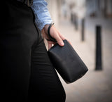 Man Holding Leather Wrist Bag from Rydal in 'Black'.