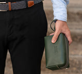 Man Gripping Leather Wrist Bag from Rydal in 'Green'.