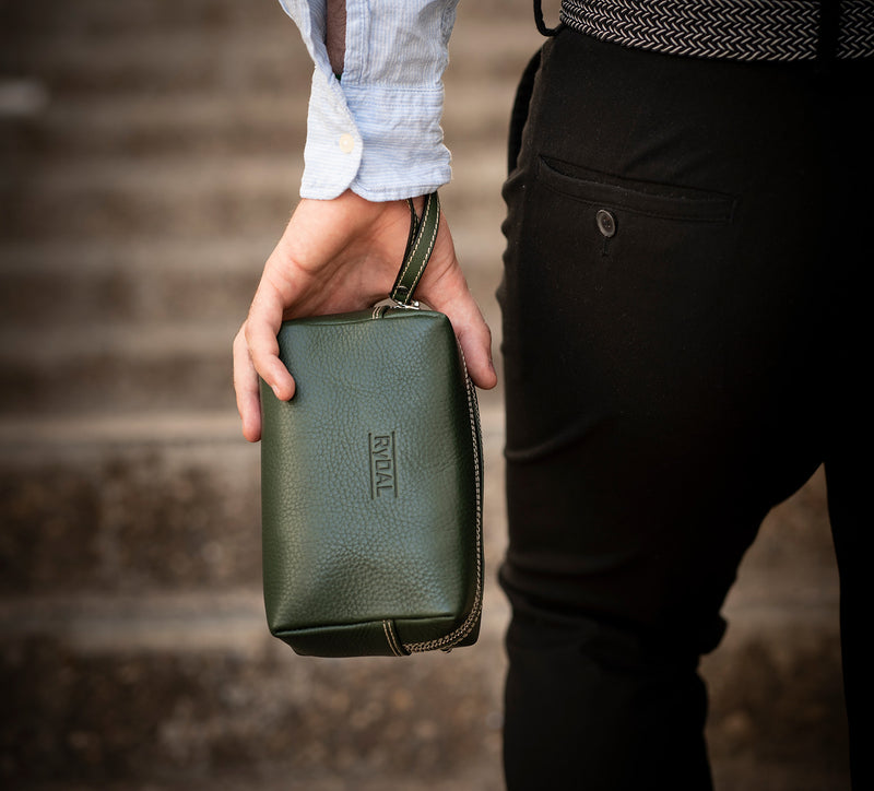 Man Carrying Leather Wrist Bag from Rydal in 'Green'.