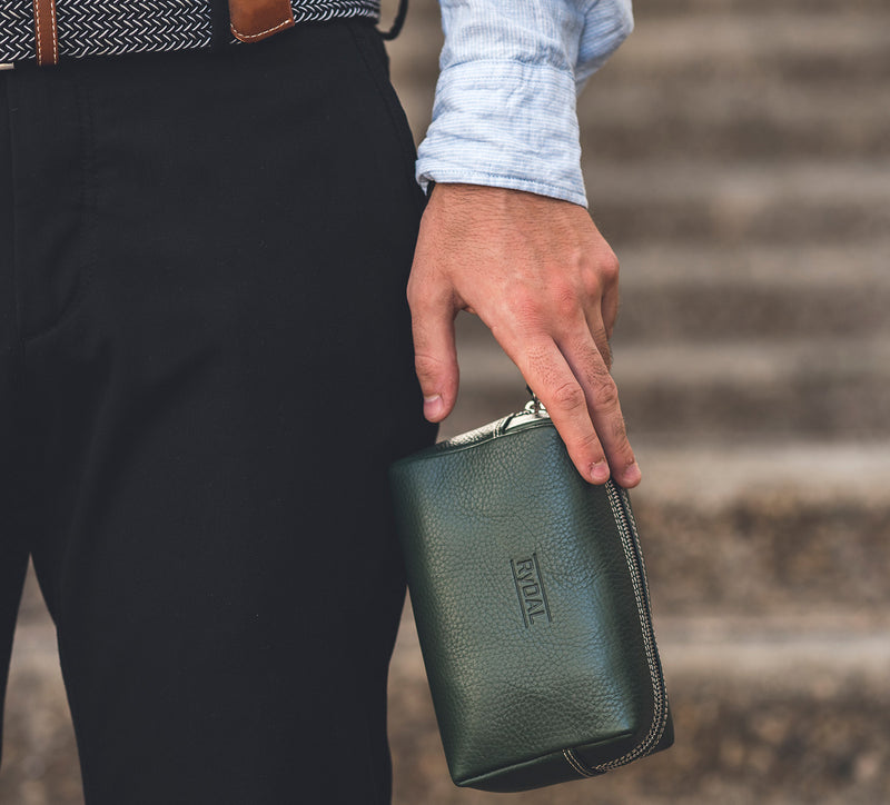 Man Holding Leather Wrist Bag from Rydal in 'Green'.