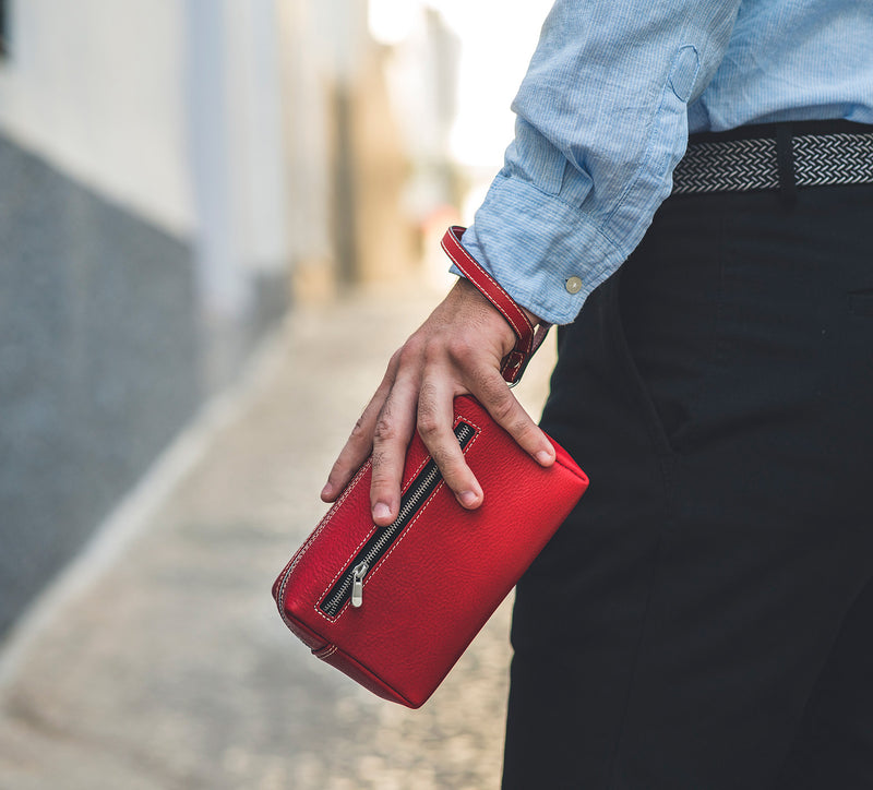 Man Gripping Leather Wrist Bag from Rydal in 'Red'.