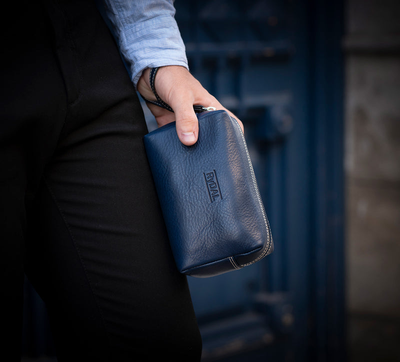 Man Gripping Leather Wrist Bag from Rydal in 'Royal Blue'.