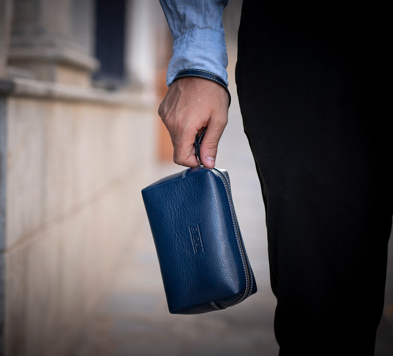 Man Holding Leather Wrist Bag from Rydal in 'Royal Blue'.