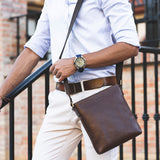 Model carrying Lucca Mens Leather Shoulder Bag from Rydal in 'Dark Brown'.